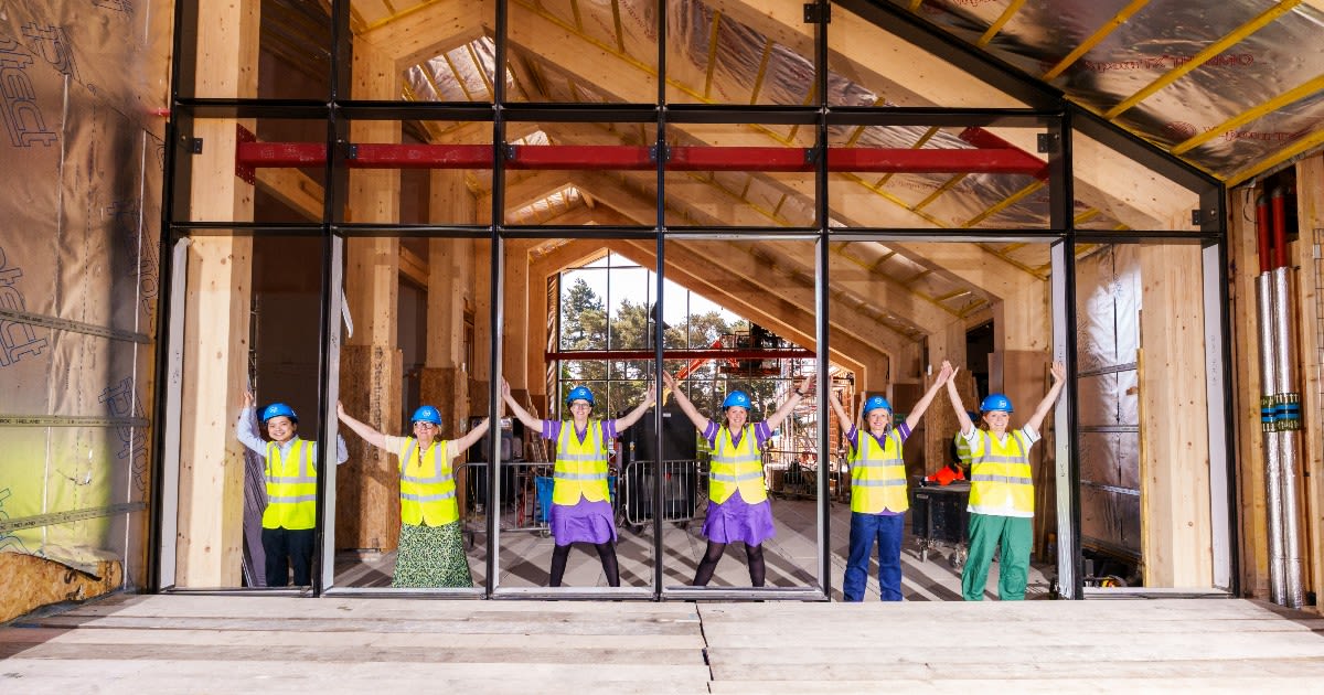 Staff from the Leeds MND service wearing high vis jackets and helmets in the frame for the windows of the Rob Burrow Centre for MND
